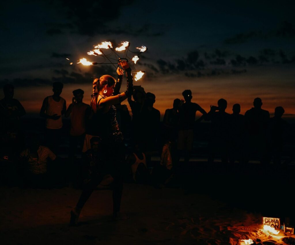 A mesmerizing fire dancer entertains a crowd at sunset on Arambol Beach, India.